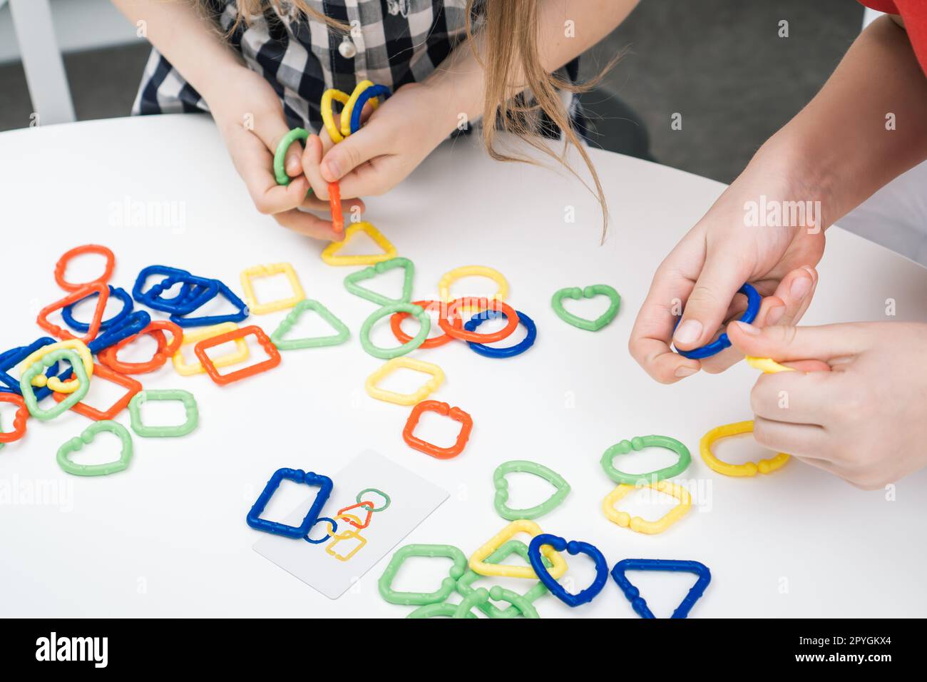 Irriconoscibile donna corta, mani femminili che collegano un colorato elemento a catena, costruttore di puzzle. Autismo e disturbo dell'adhd Foto Stock