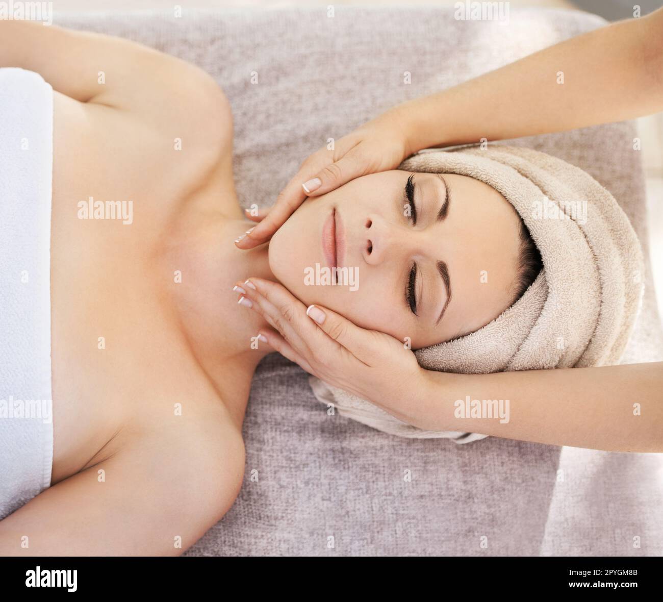 Puro relax. Una giovane donna che ottiene un massaggio del viso da un terapista di massaggio. Foto Stock