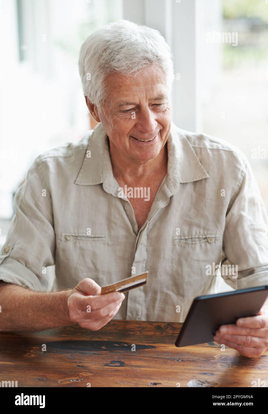 Acquistare quel regalo speciale per 50th anni... Un uomo anziano positivo che fa acquisti online con un tablet digitale. Foto Stock