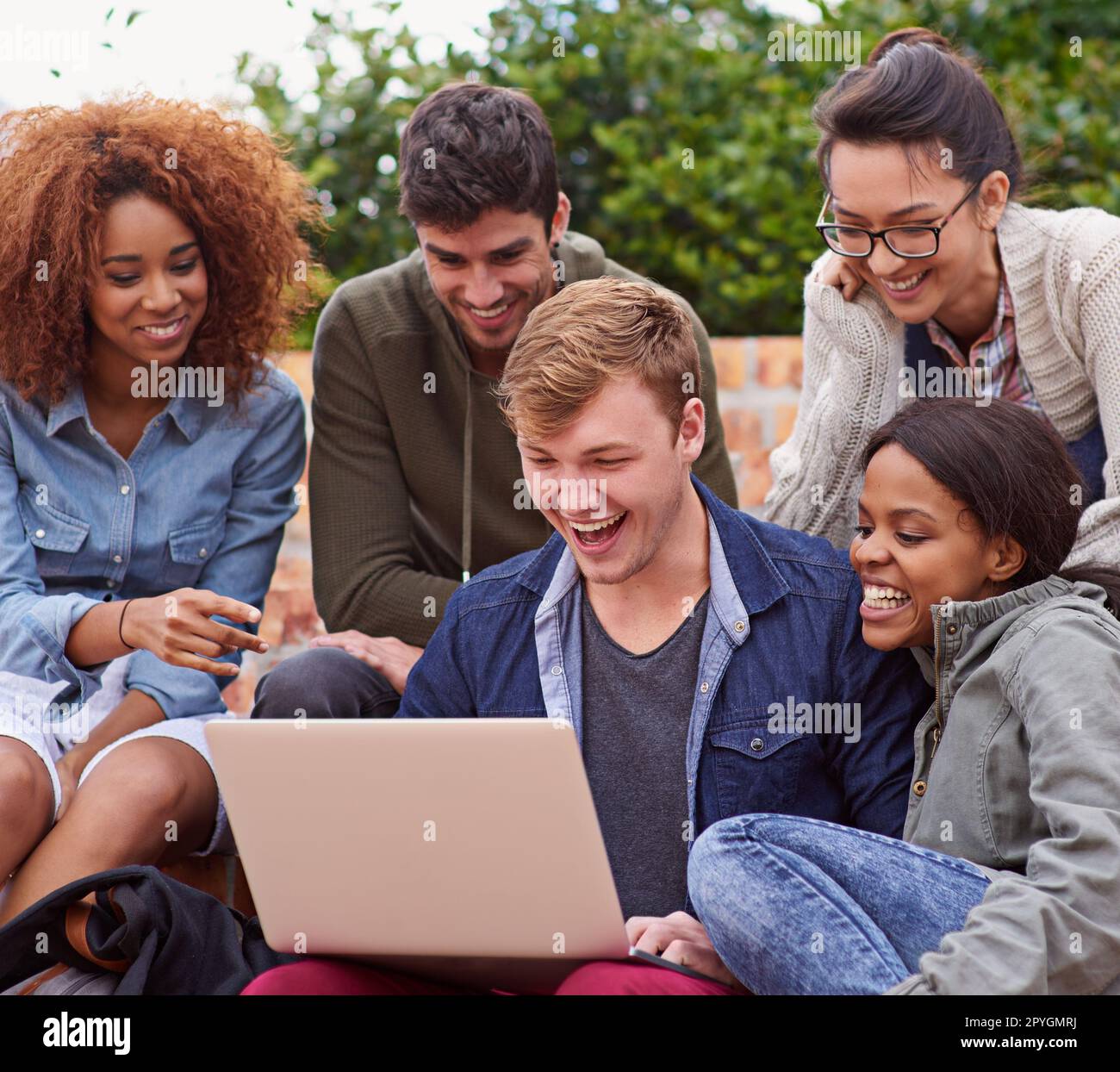 La tecnologia semplifica l'apprendimento. un gruppo di studenti seduti all'aperto mentre si trovano nel campus. Foto Stock