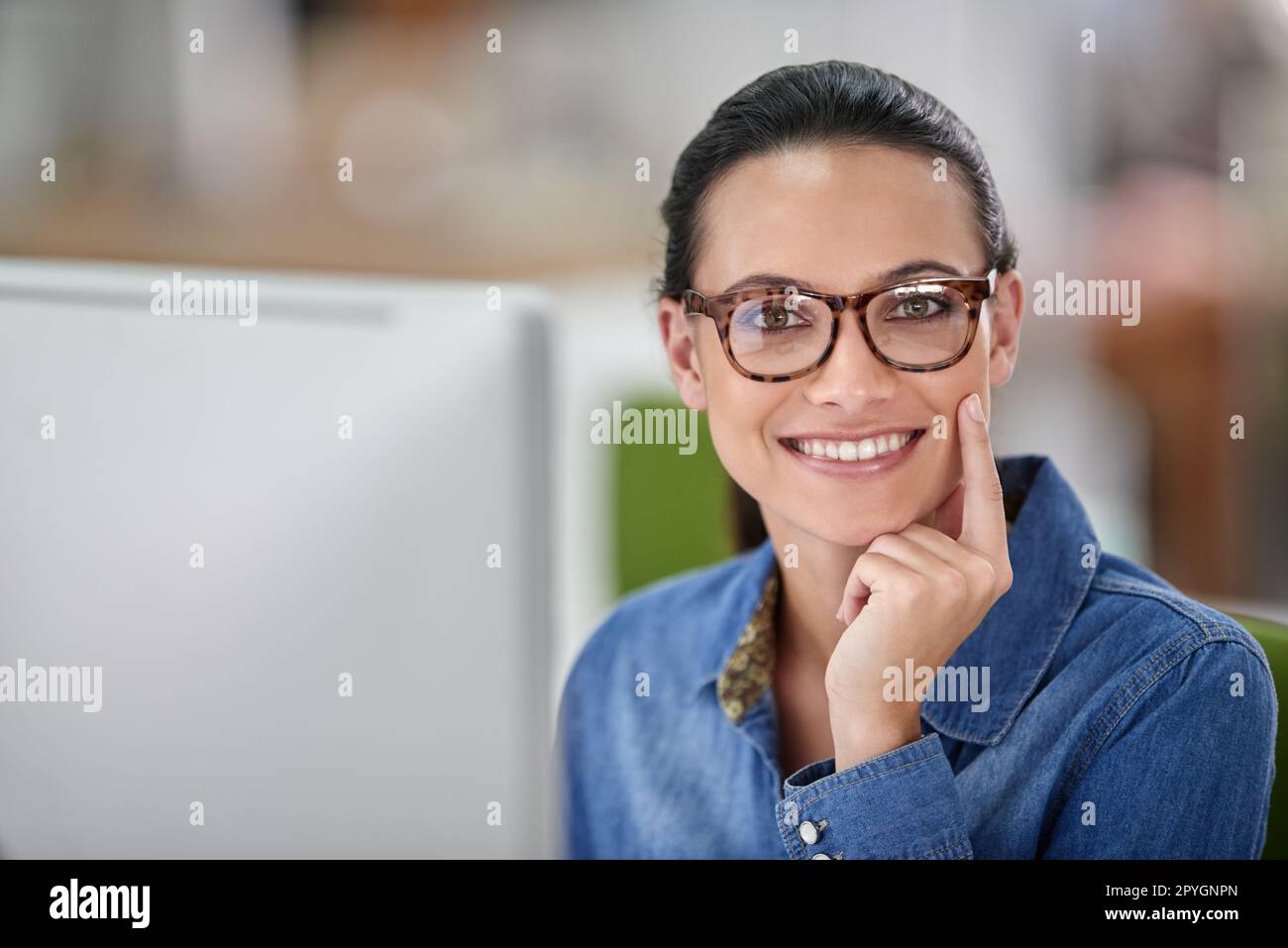 Pensiamo a questo... sorridente donna d'affari che lavora alla sua scrivania, guardando la macchina fotografica. Foto Stock