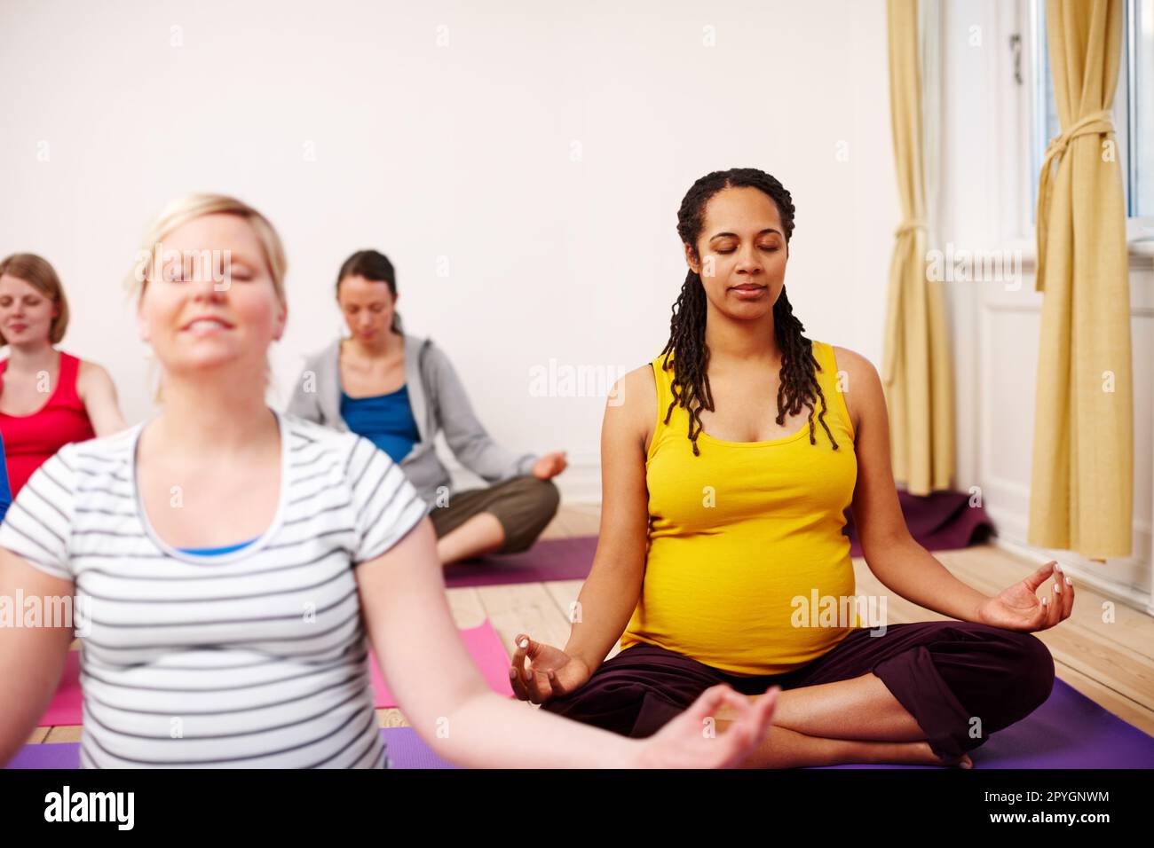 Meditazione della maternità. Un gruppo multietnico di donne incinte che meditano in una classe di yoga. Foto Stock