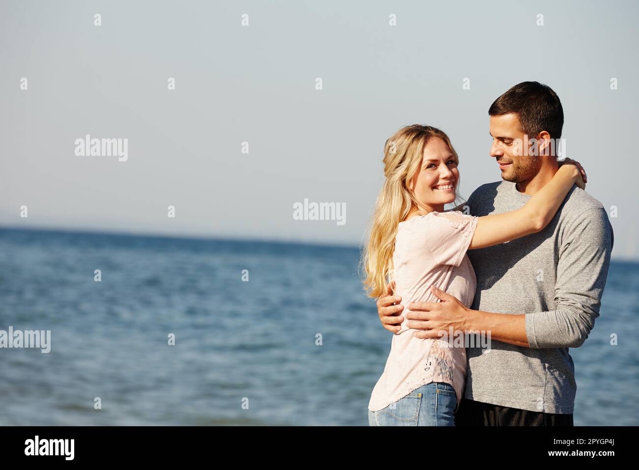 Il posto perfetto per un po' di amore. Ritratto di una giovane coppia felice che si abbraccia all'oceano. Foto Stock