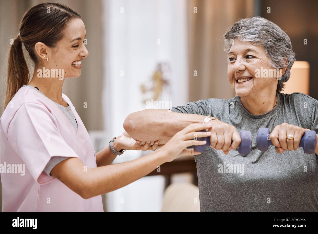 Donne, anziani o fisioterapia aiutano con il manubrio in clinica benessere, centro sanitario o casa di cura soggiorno. Sorriso, infermiera felice o fisioterapista e paziente anziano in riabilitazione del peso Foto Stock