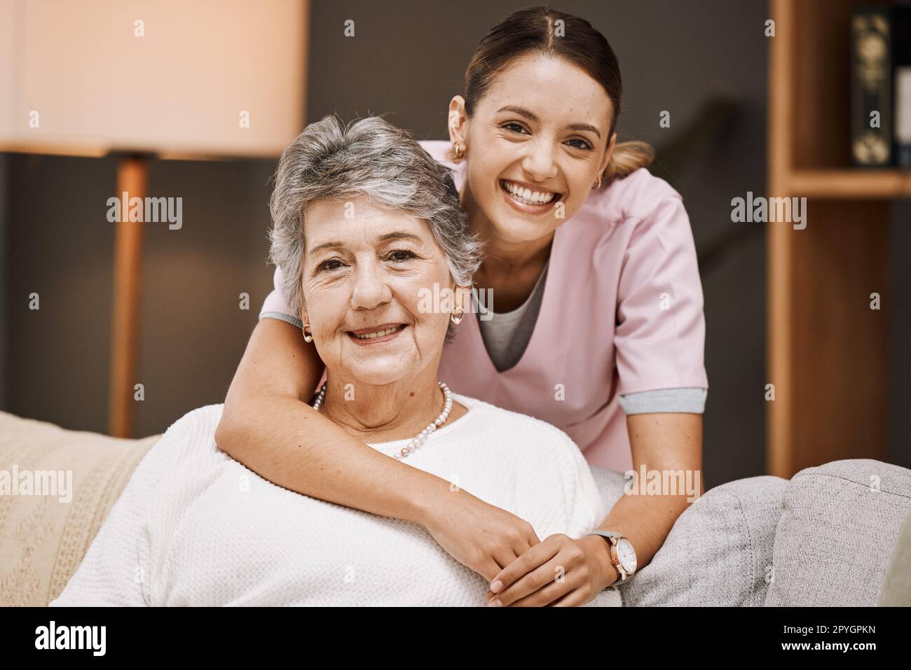 Sostegno, ritratto e infermiera con una donna anziana su un divano nel soggiorno di una casa di cura. Assistenza sanitaria, benessere e caregiver che abbraccia una donna anziana pensionato in casa di riposo o clinica. Foto Stock