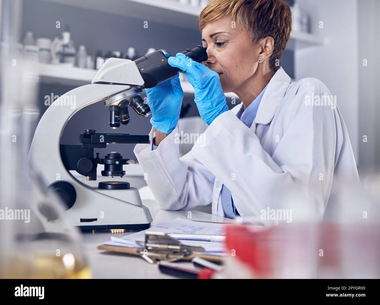 Scienza, laboratorio e donna nera con microscopio, ricerca per lo sviluppo di vaccini. Sanità, innovazione medica e donna scienziata senior in laboratorio ospedaliero che guarda i risultati dei test farmaceutici Foto Stock