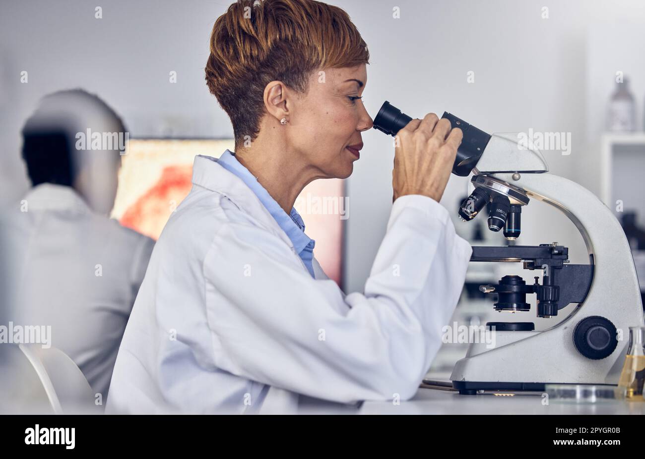 Scienza, laboratorio e donna nera con microscopio, ricerca per lo sviluppo di vaccini. Sanità, innovazione medica e donna scienziata senior in laboratorio ospedaliero che guarda i risultati dei test farmaceutici Foto Stock