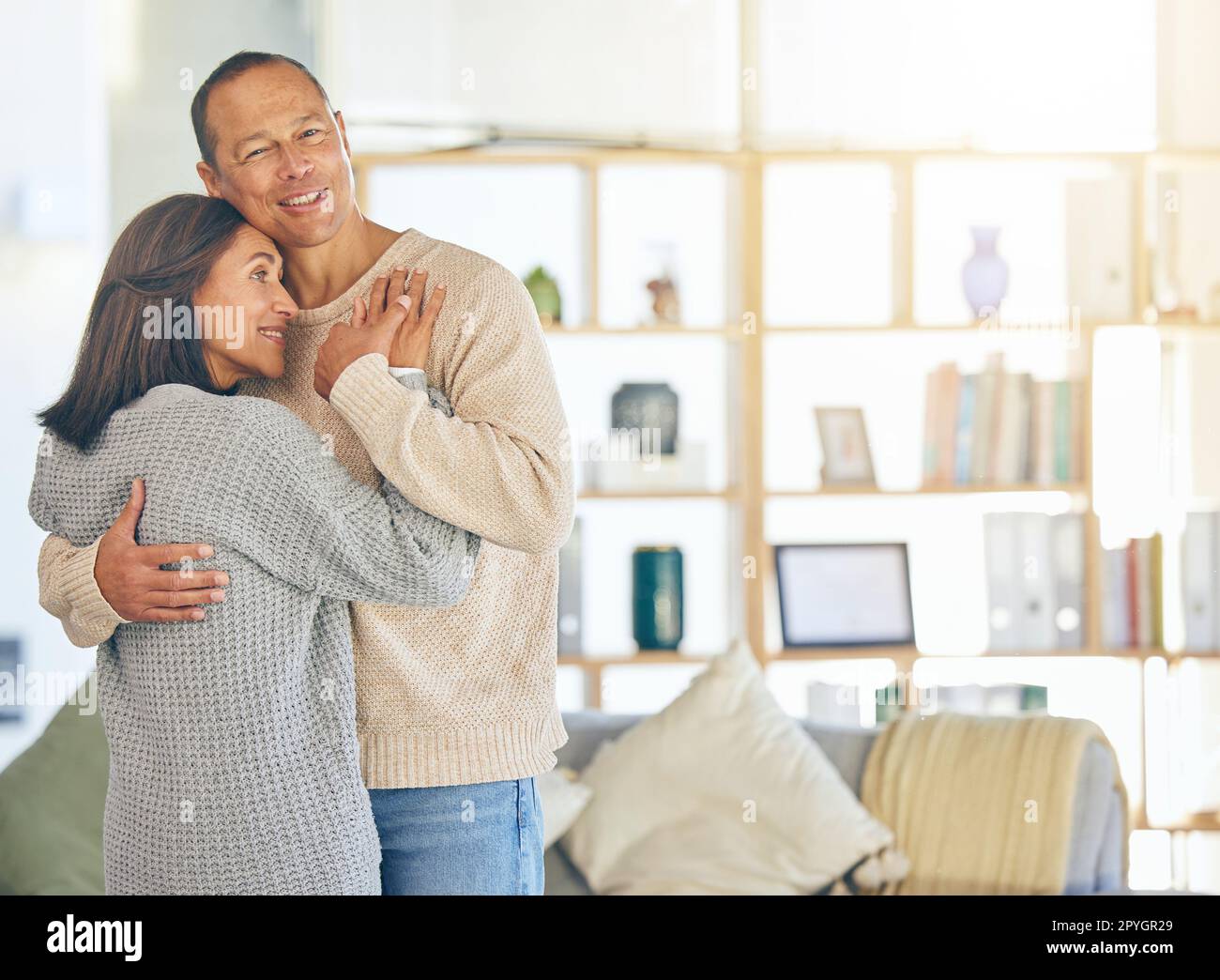 Amore, romanticismo e matrimonio con una coppia che si abbraccia in casa con un mockup o un flare. Affetto, legame e abbraccio con un uomo e una donna maturi che si abbracciano nella loro casa Foto Stock