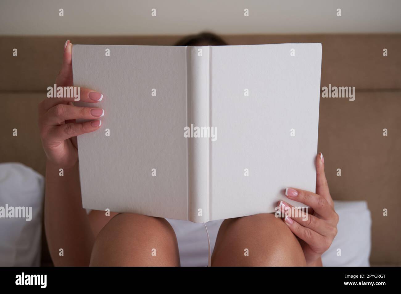 Giovane donna che tiene in mano un notebook vuoto o un libro mockup, mostrando il design della copertina. Foto Stock