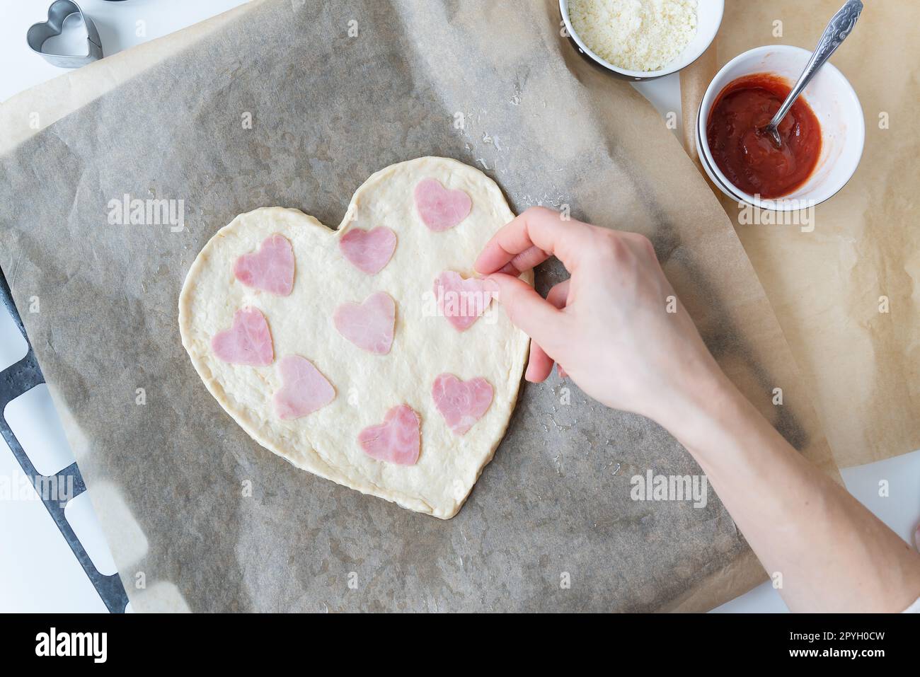 Impasto per pizza a forma di cuore, lo chef prepara salsicce a forma di cuore. Pizza italiana, pizza a forma di cuore. Foto Stock