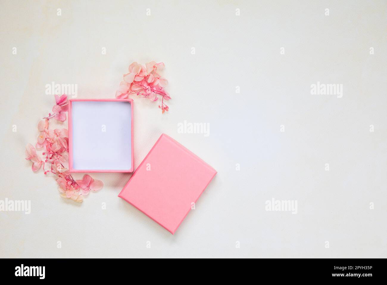 Scatola regalo rosa aperta e chiusa per il prodotto su sfondo luminoso con fiori. Piano, vista dall'alto, regalo mock-up, regalo della mamma, San Valentino, concetto di compleanno Foto Stock