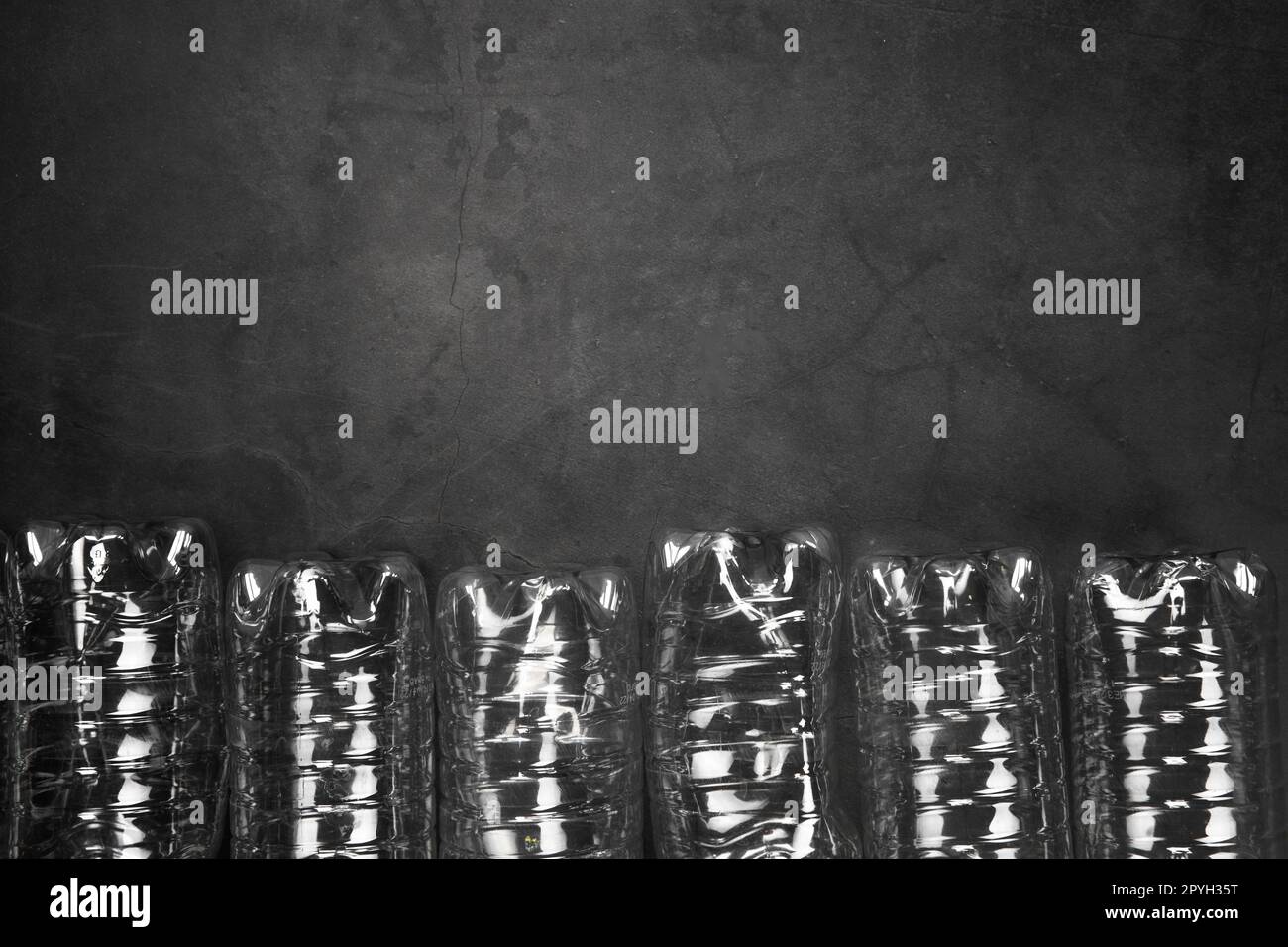 Concetto di riciclaggio ed ecologia. Smistamento rifiuti domestici catturati dall'alto, giacitura. Bottiglie di plastica vuote con fondo in cemento grigio Foto Stock