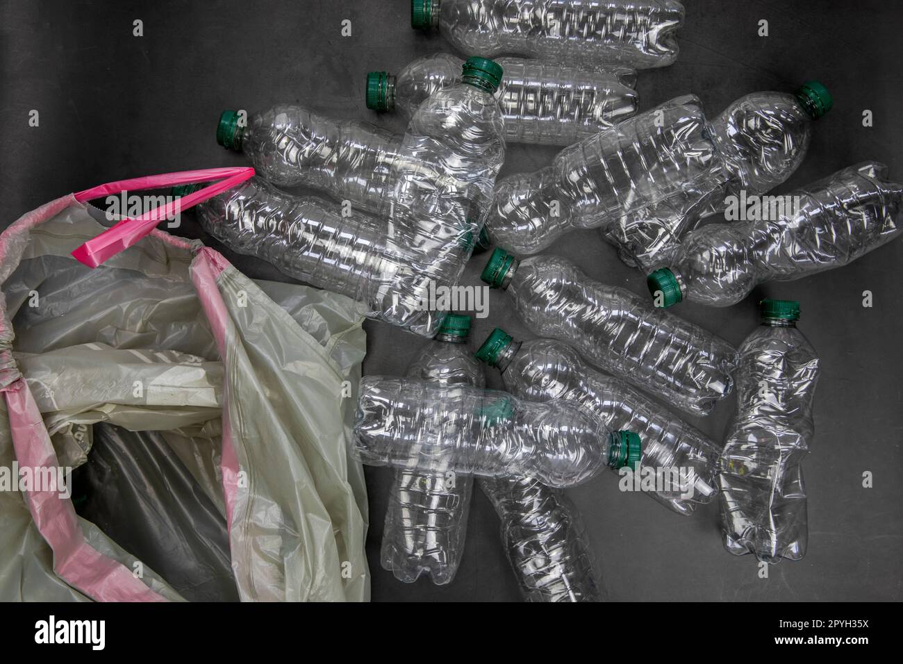 Concetto di riciclaggio ed ecologia. Smistamento rifiuti domestici catturati dall'alto, giacitura. Bottiglie di plastica vuote con fondo in cemento grigio Foto Stock