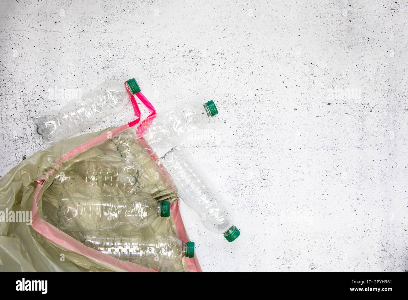 Concetto di riciclaggio ed ecologia. Smistamento rifiuti domestici catturati dall'alto, giacitura. Bottiglie di plastica vuote con fondo in cemento bianco Foto Stock