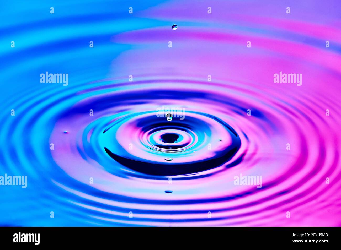 una goccia d'acqua che cade nell'acqua e crea onde Foto Stock