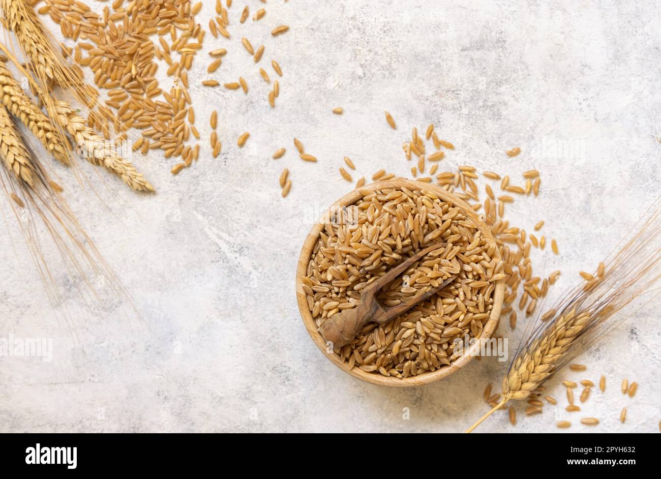 Recipiente di grano di segale secco crudo con cucchiaio di legno sulla vista bianca del piano d'esame Foto Stock