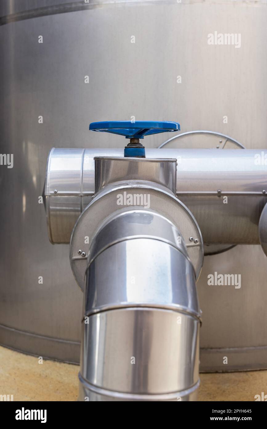 Valvola e tubi in metallo blu di tipo volantino, apparecchiature industriali presso la fabbrica di vino, primo piano Foto Stock
