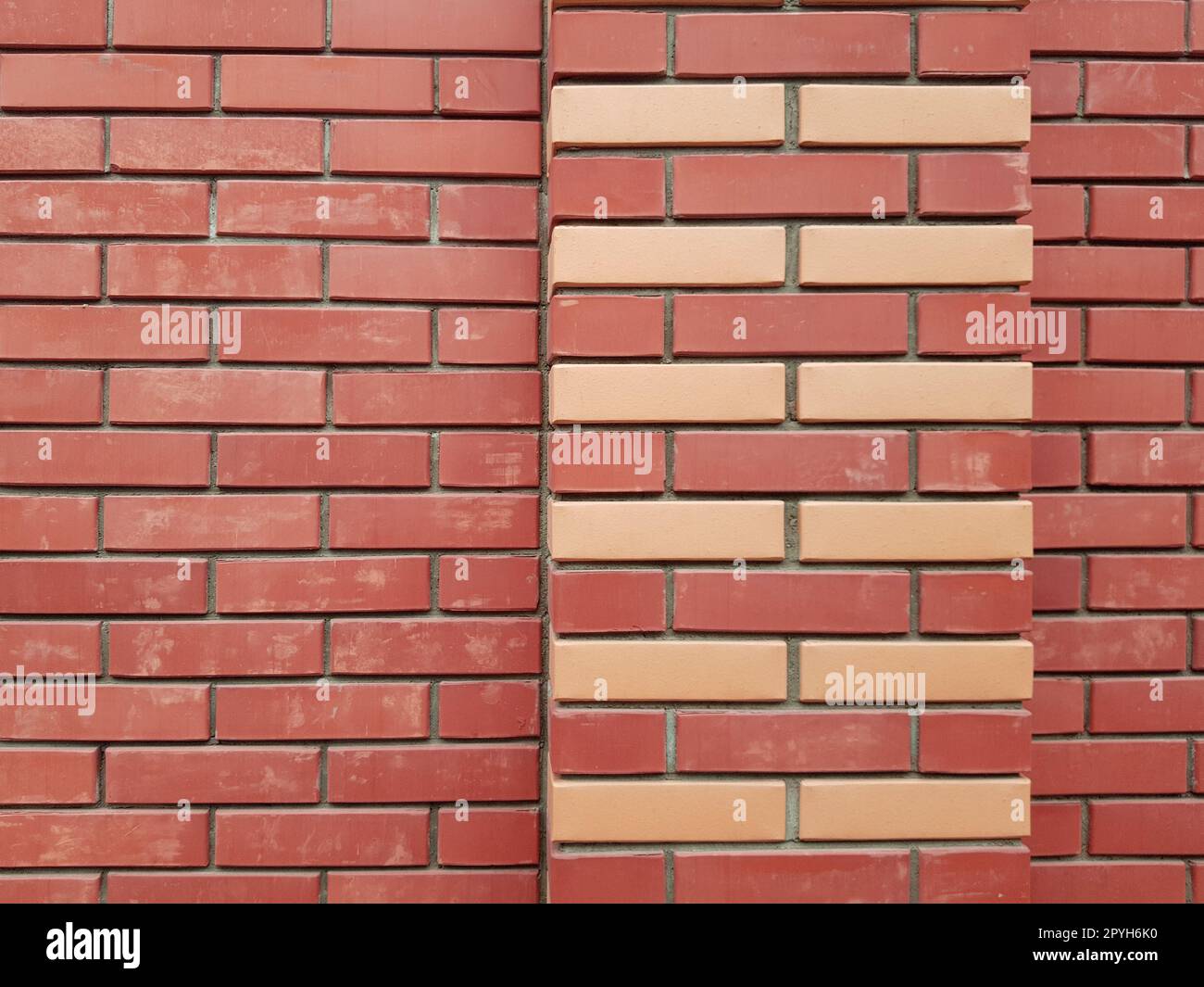 La struttura moderna di una parete di mattoni rossi con ornamenti di mattoni gialli è il materiale di fondo della costruzione industriale Foto Stock