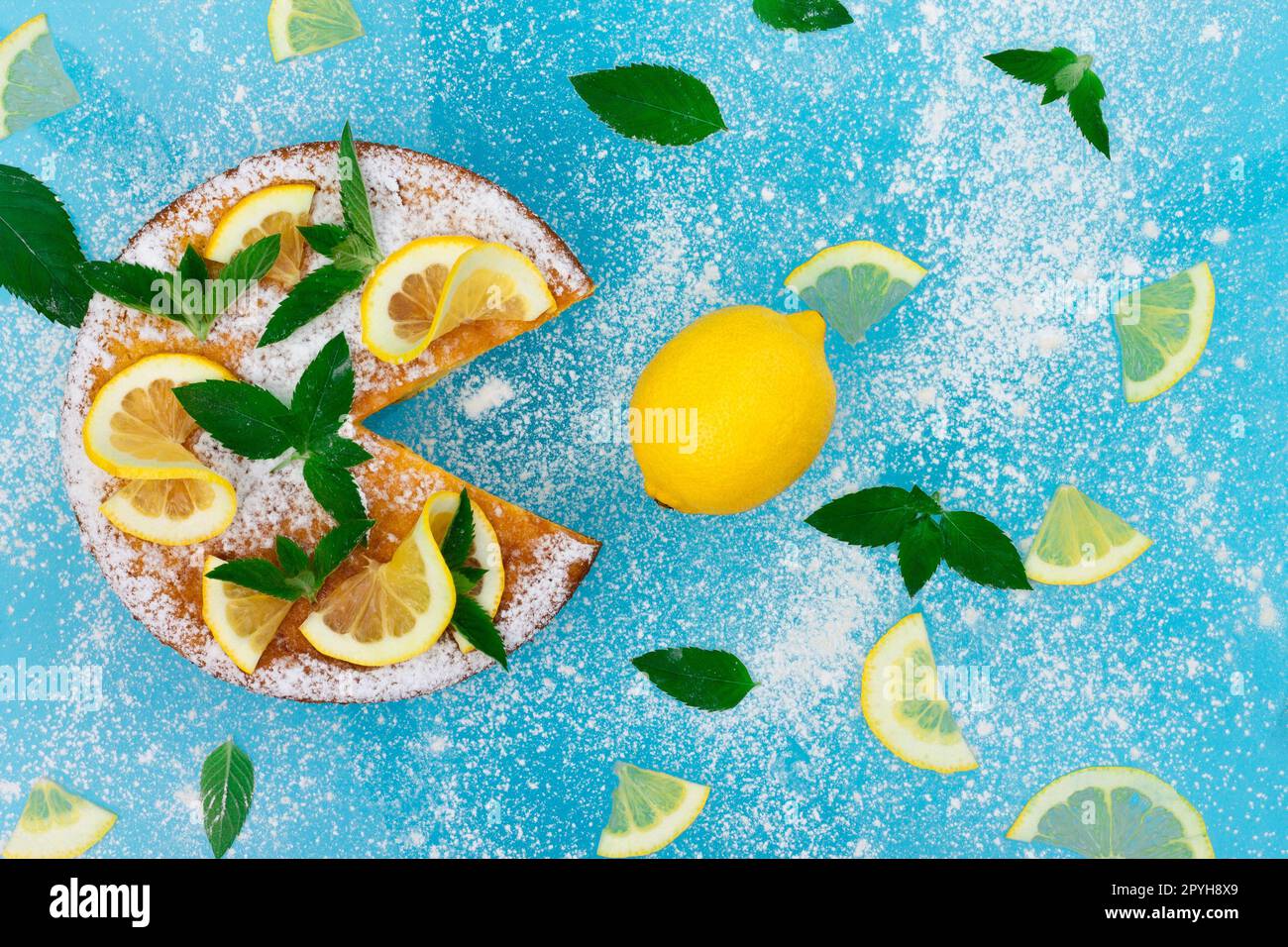 Torta di limone con fette di limone, menta e zucchero in polvere su sfondo blu. Vista dall'alto. Copia spazio. Foto Stock