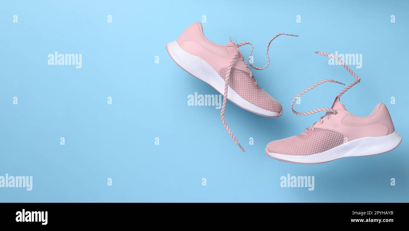 Le sneaker sportive rosa da donna con lacci si fondono su uno sfondo blu Foto Stock