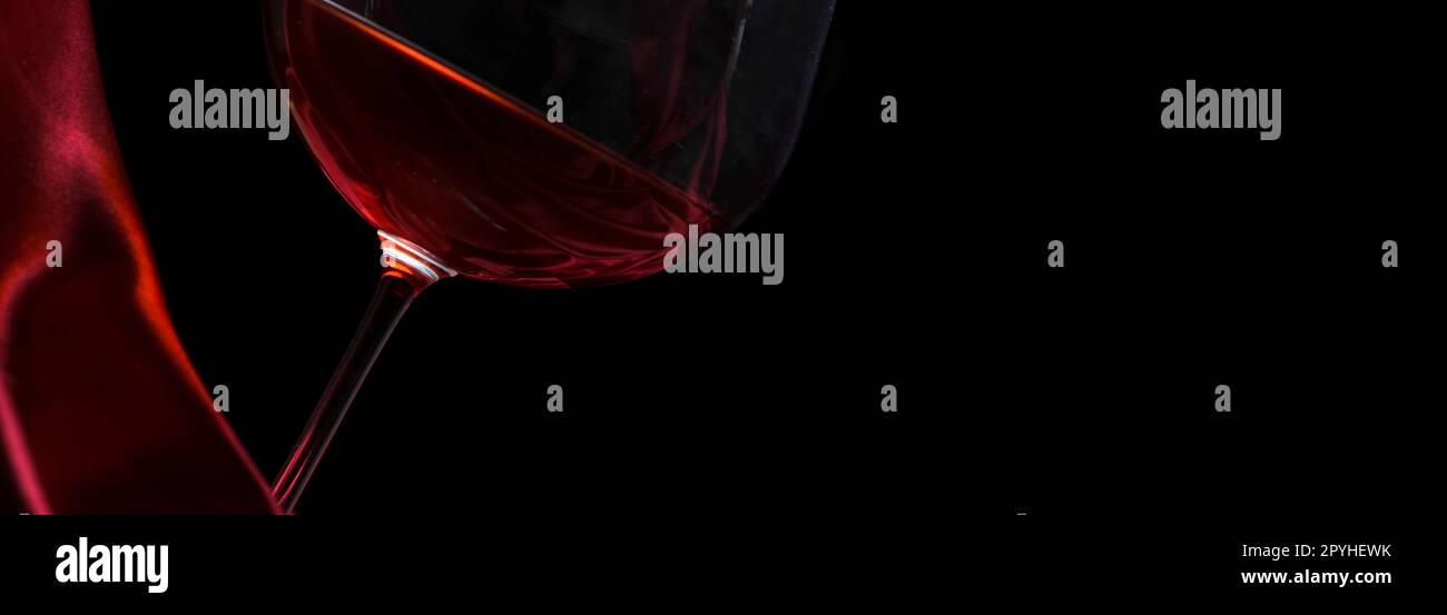 Bicchiere di vino rosso in seta rosso su sfondo nero. Lista dei vini background di design. Foto Stock