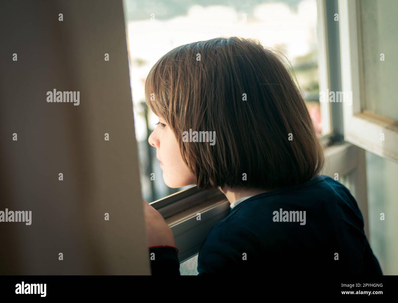 Bambina guardando fuori dalla finestra Foto Stock