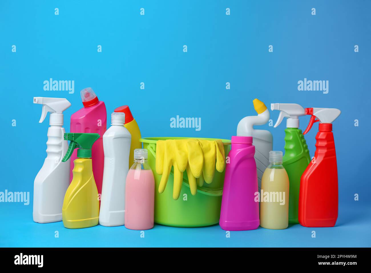Secchio verde, guanti e bottiglie di detersivi su sfondo azzurro. Pulizia  dei materiali di consumo Foto stock - Alamy