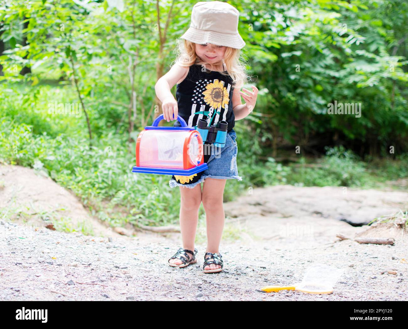 Bambina caucasica in esplorazione all'aperto. Elenco dei secchielli estivi per bambini Foto Stock
