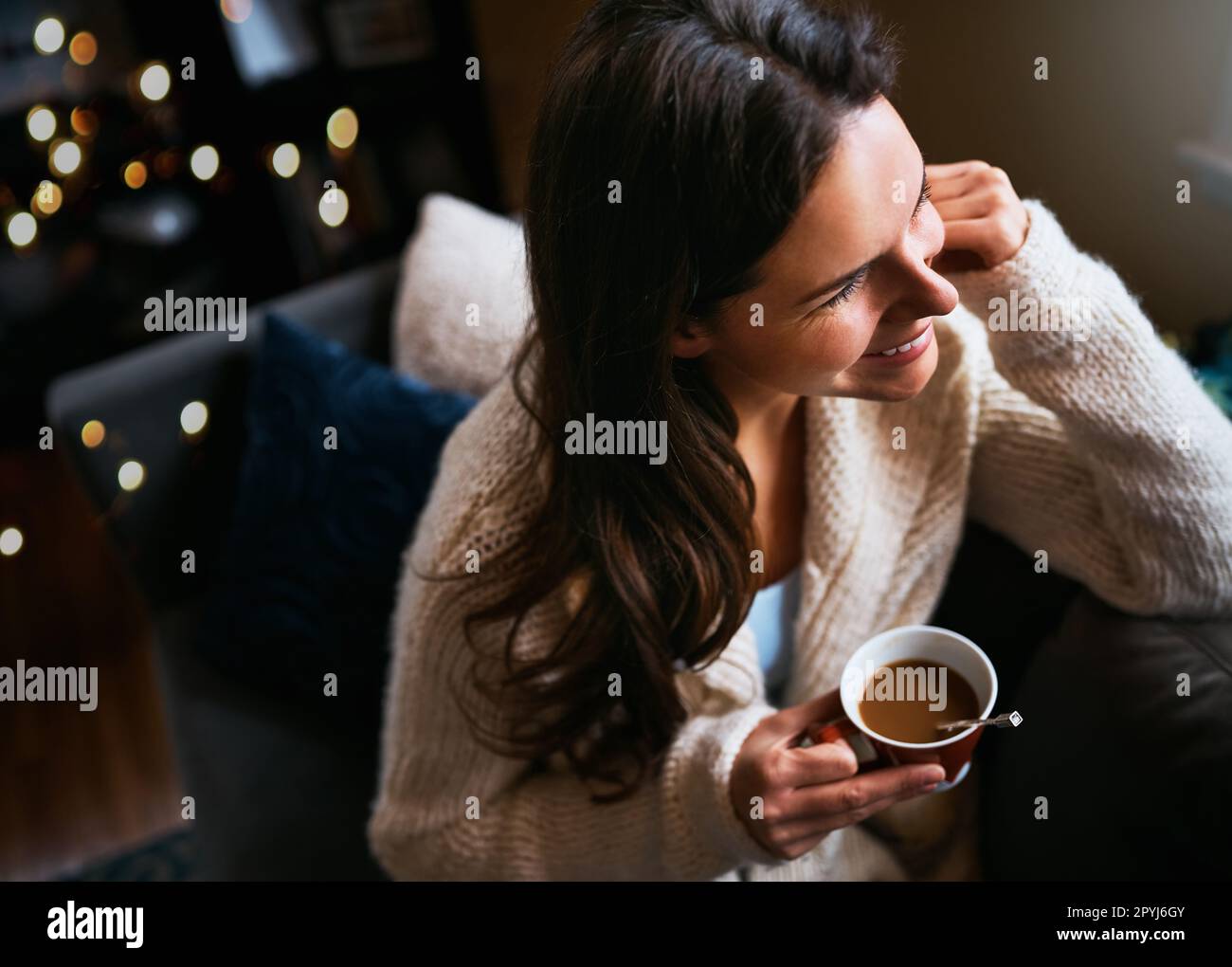 Il fine settimana è il momento di rallentare. una giovane donna attraente che si rilassa sul divano con una tazza di caffè a casa. Foto Stock