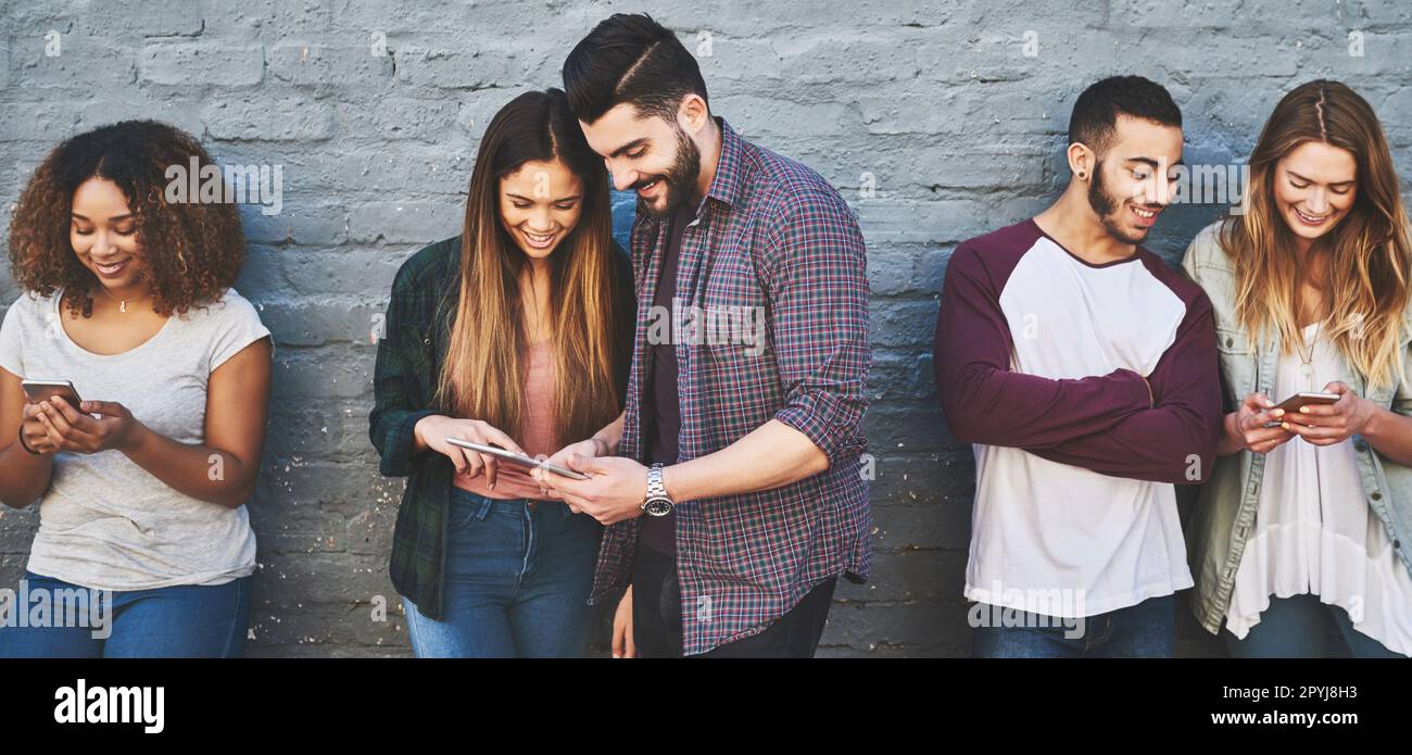 La rete è il nuovo luogo di ritrovo. un gruppo di giovani amici che utilizzano i loro dispositivi wireless insieme all'aperto. Foto Stock