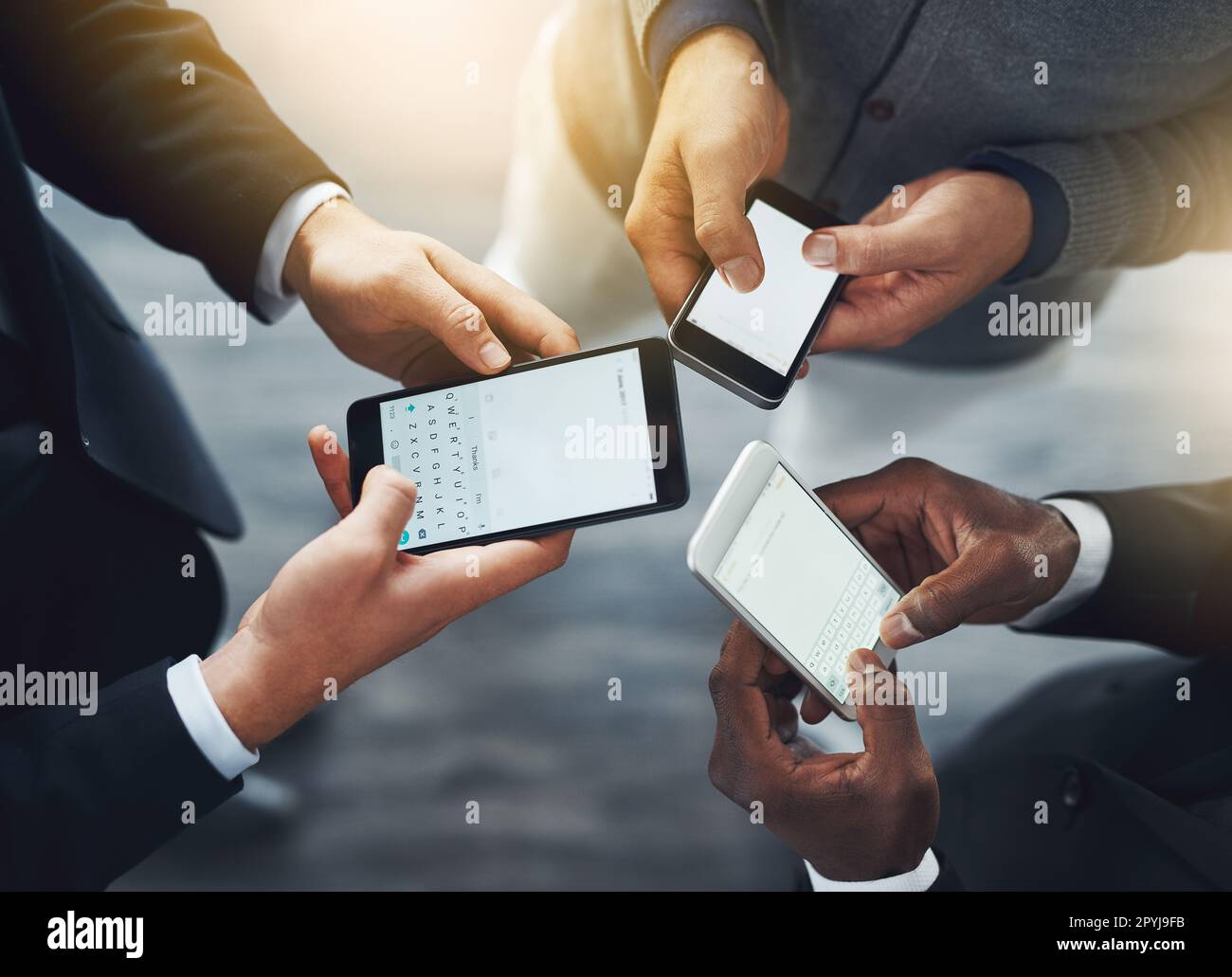 L'integrazione intelligente e perfetta della tecnologia nel luogo di lavoro. un gruppo di uomini d'affari irriconoscibili che usano i loro cellulari in sincronia. Foto Stock