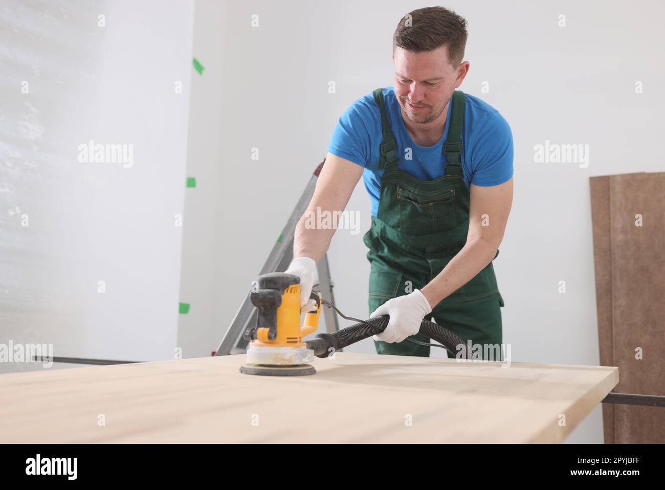 Il falegname lucida la tavola in legno con una moderna smerigliatrice Foto Stock