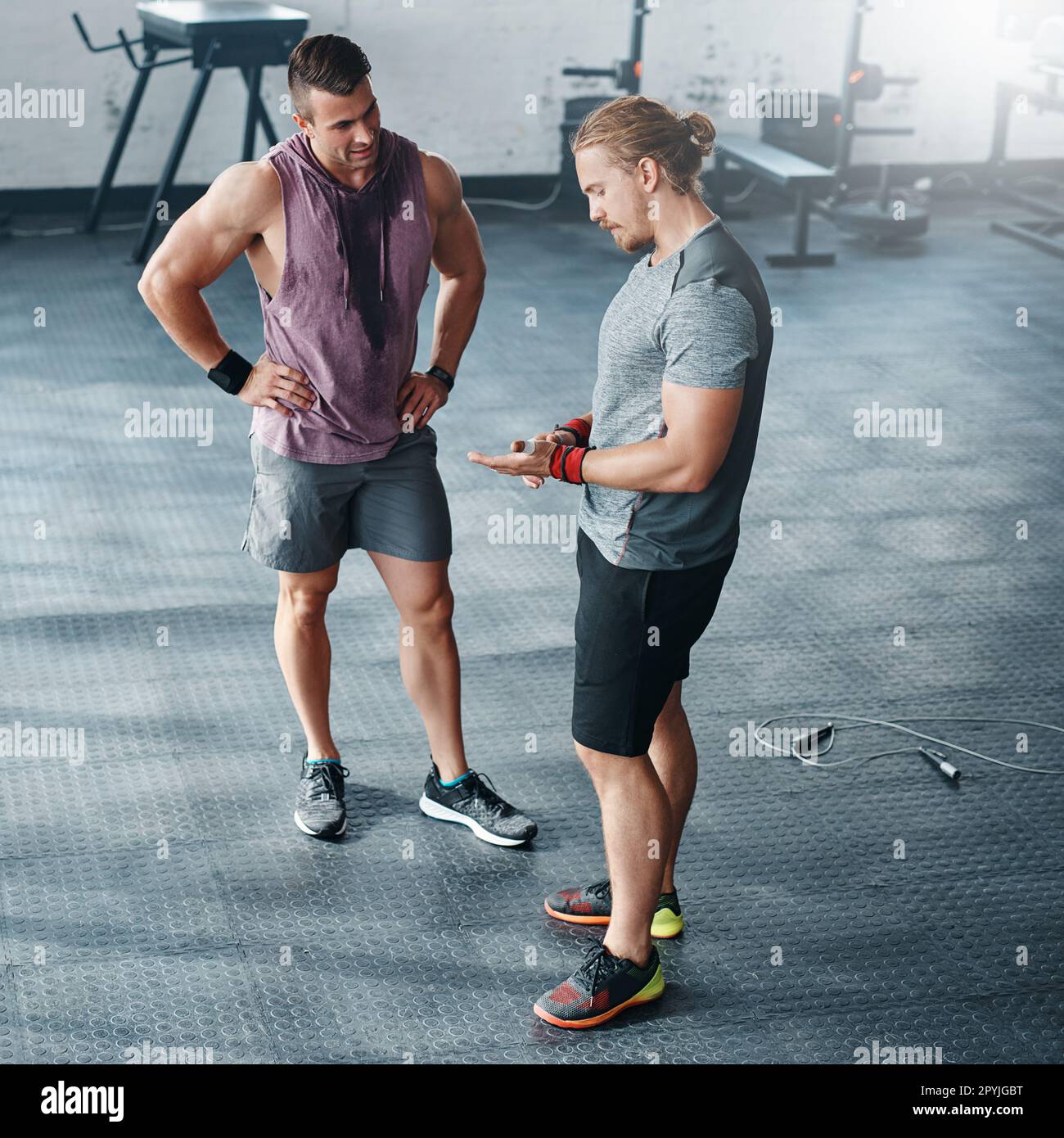 Discutere dei modi per migliorare la loro routine. due giovani che chiacchierano in palestra. Foto Stock