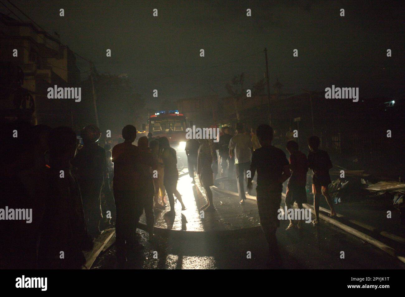Silhouette di persone in piedi e a piedi sulla strada dopo un incidente di incendio ha bruciato un quartiere denso a Penjaringan, a nord di Giacarta, Indonesia. Foto Stock