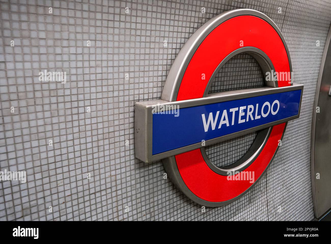 Londra, Regno Unito - 02 febbraio 2019: Cartello illuminato della stazione della metropolitana di Waterloo alla parete della fermata della metropolitana. Design tradizionale rosso, bianco e blu Foto Stock