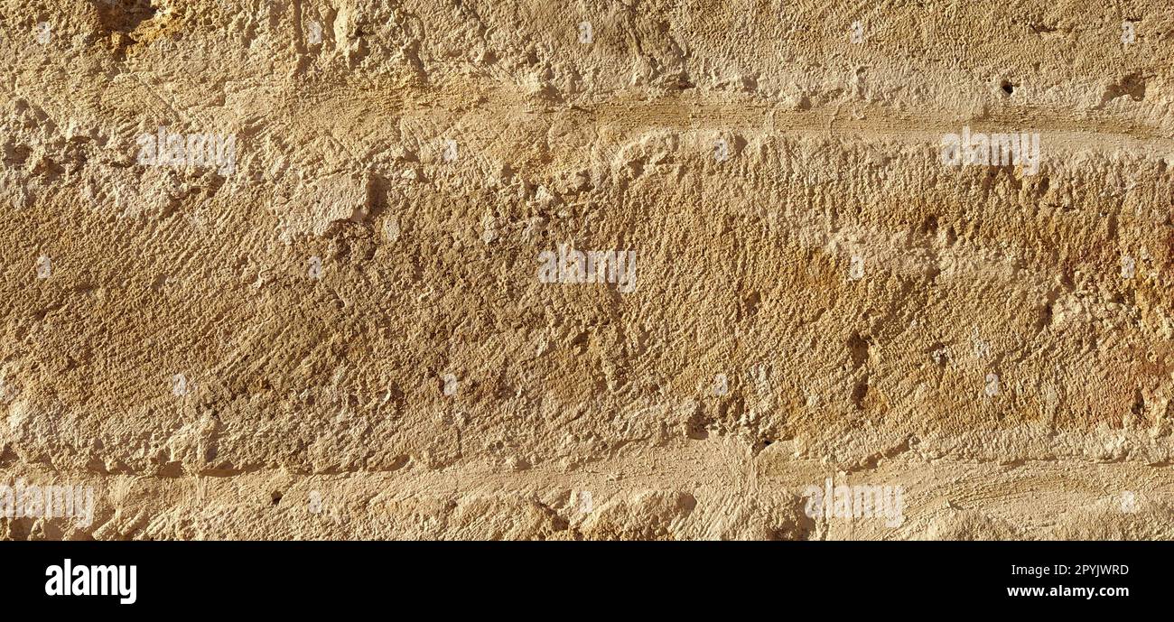 Bellissima pietra arenaria, sabbia compatta. Struttura in pietra su un antico monumento in marmo. Colore giallo brillante, superficie ruvida, danni individuali sull'aereo. Il sole della sera. Architettura antica Foto Stock