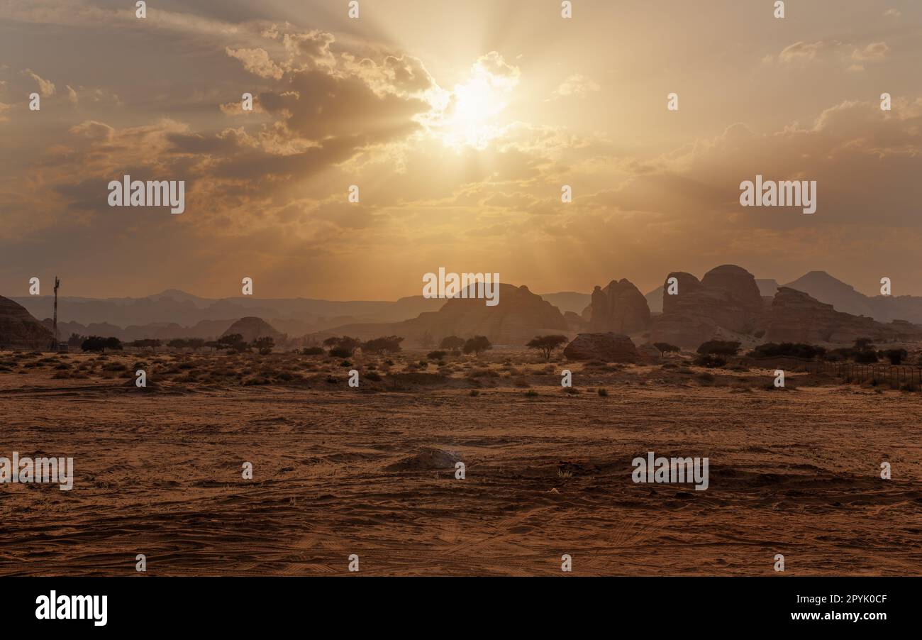 Paesaggio tipico nella regione di Alula vicino al sito archeologico di Hegra Mada'in Salih poco prima del tramonto - deserto arido sabbioso con pochi alberi e piccole montagne a distanza Foto Stock