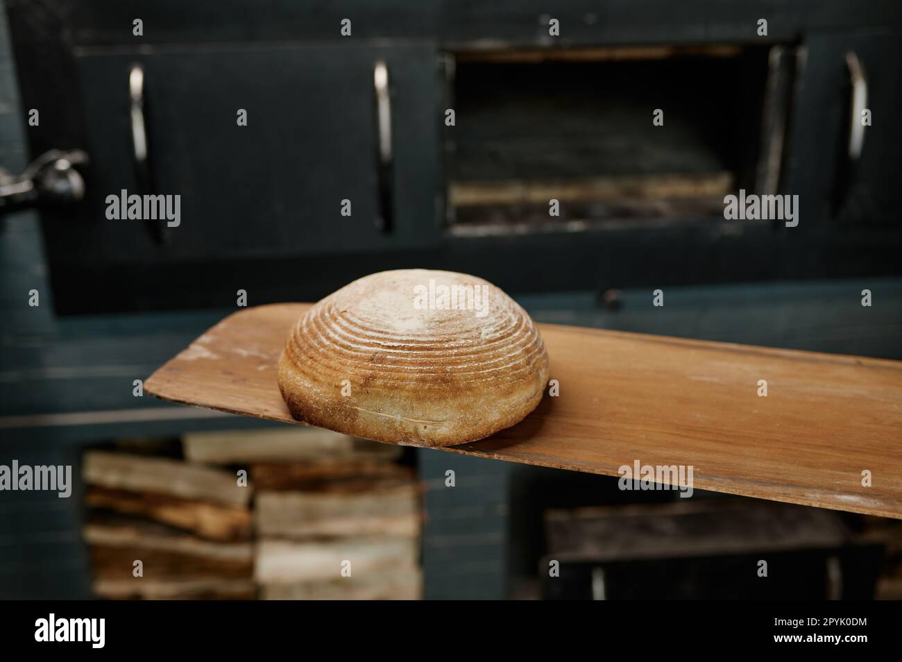 Closeup pane fresco cotto su spatola di legno su stufa aperta calda Foto Stock