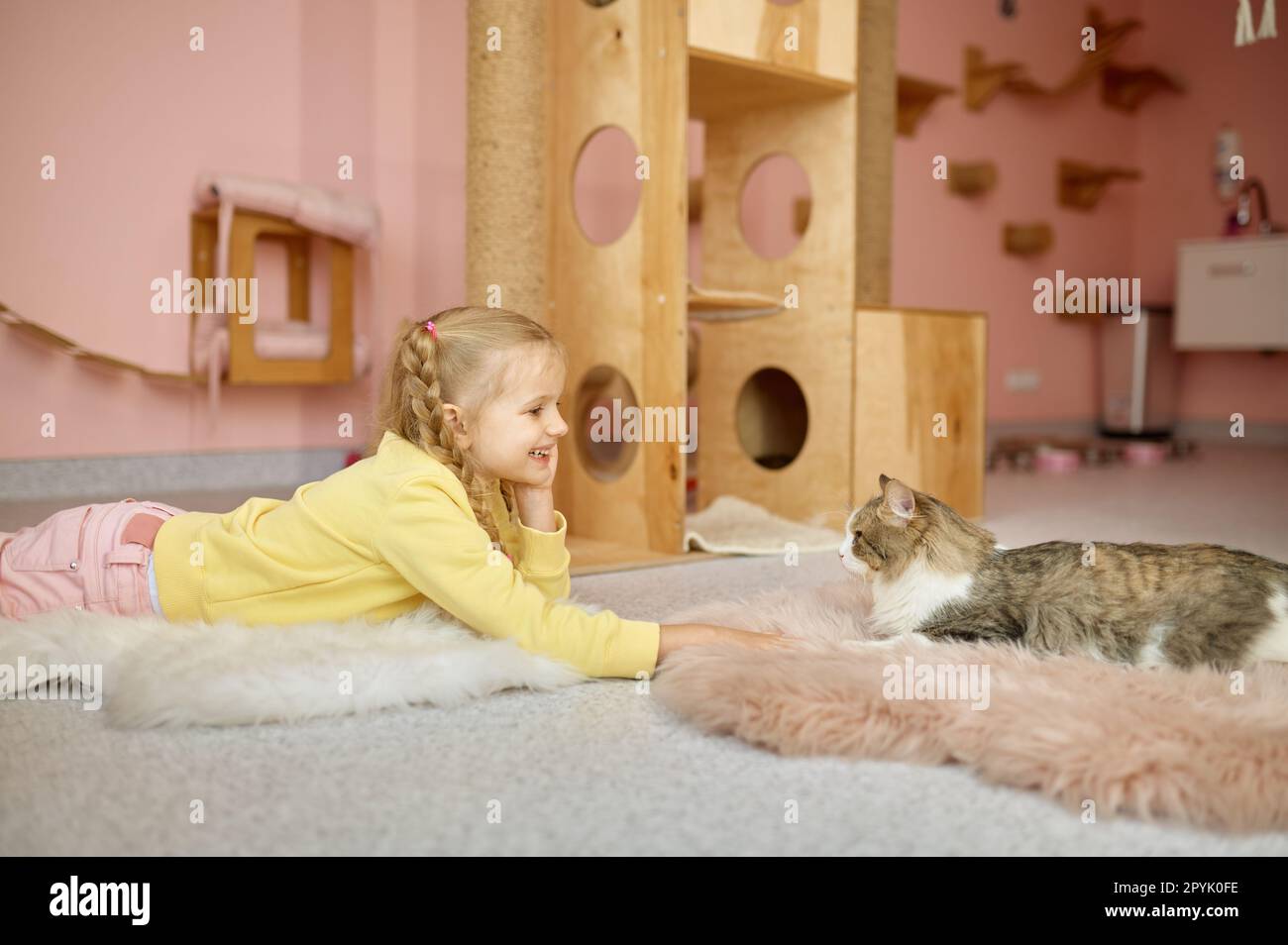 Bambina che guarda come il gatto strisciare fuori dalla gabbia trascorrere il tempo allo zoo degli animali domestici Foto Stock