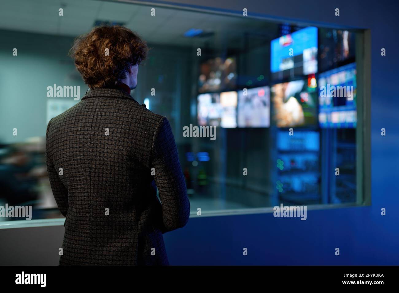 Uomo che guarda la riflessione dello schermo del computer nella finestra della stanza del server Foto Stock