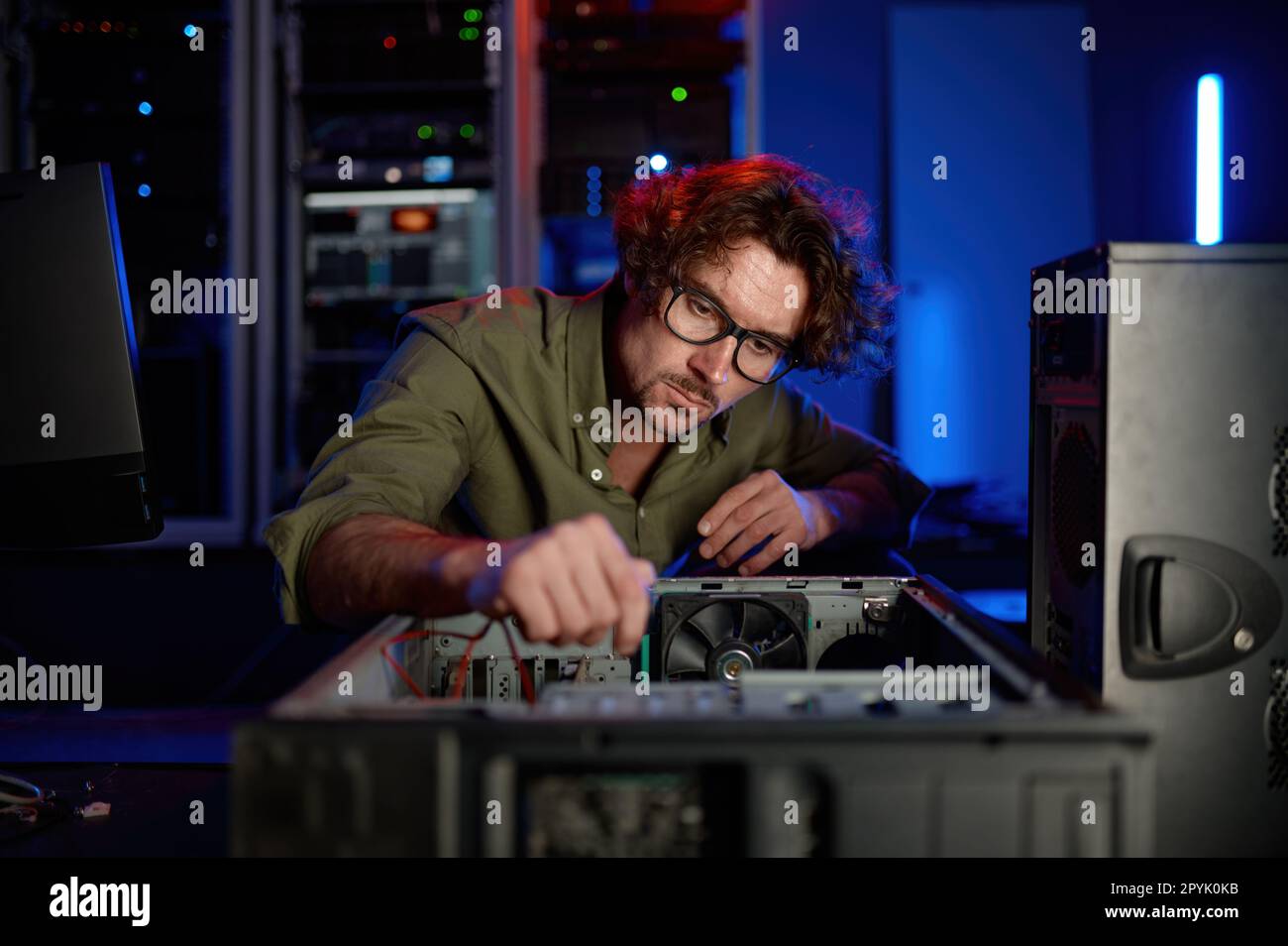 Uomo che ripara l'unità del computer nel moderno centro di assistenza Foto Stock