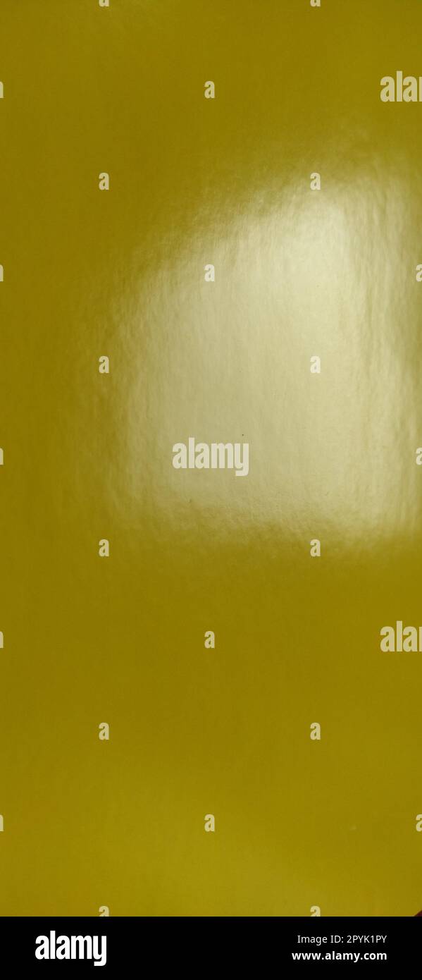 Bel fondo giallo. Primo piano di un foglio di carta. Colore puro e allegro. Tonalità di giallo brillante, simile a un colore scuro e brillante. Riflesso della luce su una superficie lucida. Verticale Foto Stock