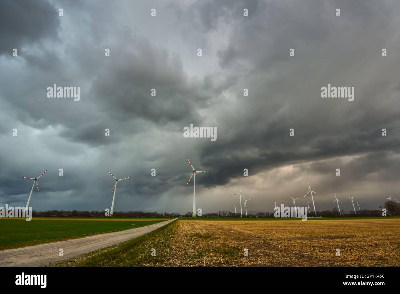 nuvole di pioggia nere scure con molti mulini a vento e una strada sterrata Foto Stock