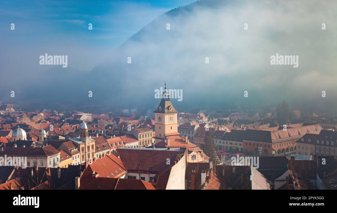 Vista di Brasov, Romania, montagne e nebbia, splendido centro storico con case arancioni Foto Stock