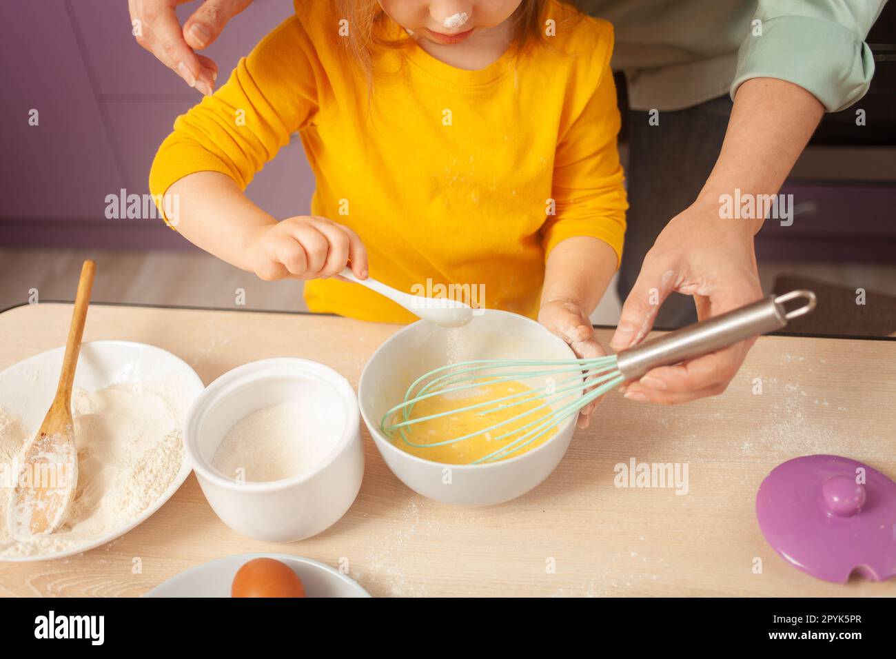 Nonna e nipote preparano l'impasto, trascorrono del tempo insieme, le relazioni di famiglia, l'amore. cucchiaio con zucchero. Foto Stock