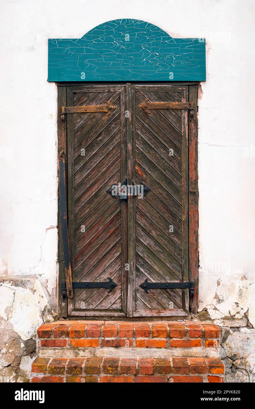 Una vecchia porta di legno con scale rosse in mattoni Foto Stock