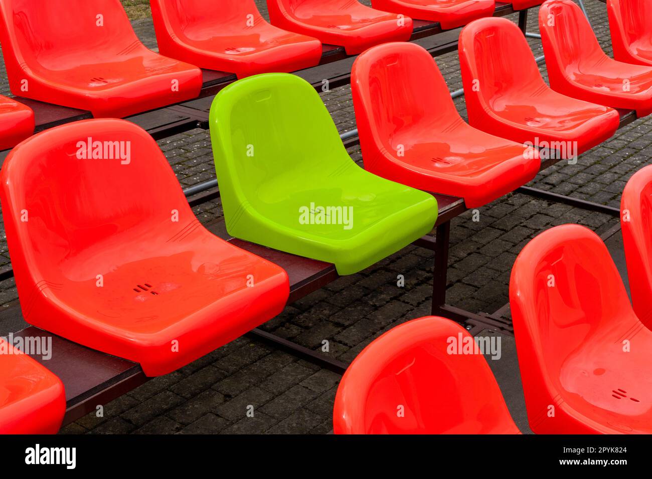 Un posto a sedere verde tra i sedili di colore rosso in uno stadio Foto Stock