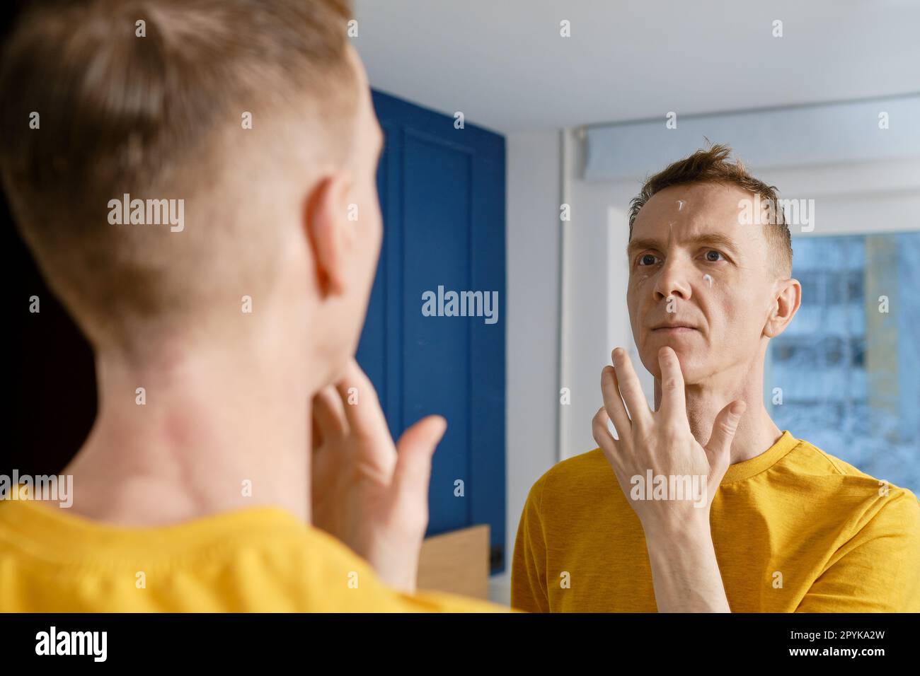 Uomo di mezza età che applica crema antirughe Foto Stock