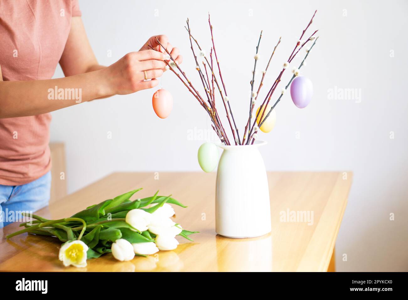 Mani femminili da fioraio che decorano un bouquet di rami di salice con uova di Pasqua colorate. Foto Stock