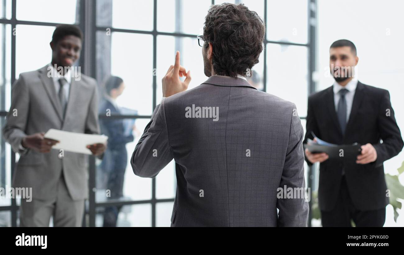 un uomo si alza con la schiena sullo sfondo dei suoi colleghi Foto Stock